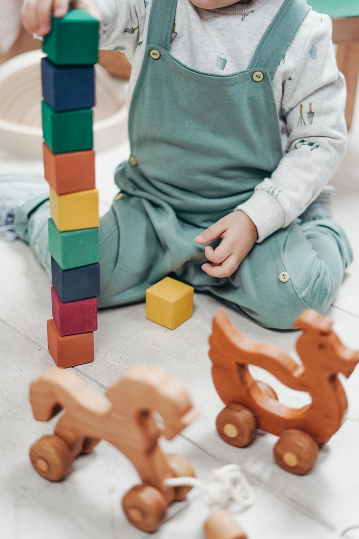 about-me-img A child enjoying playtime indoors with colorful wooden blocks and toys.