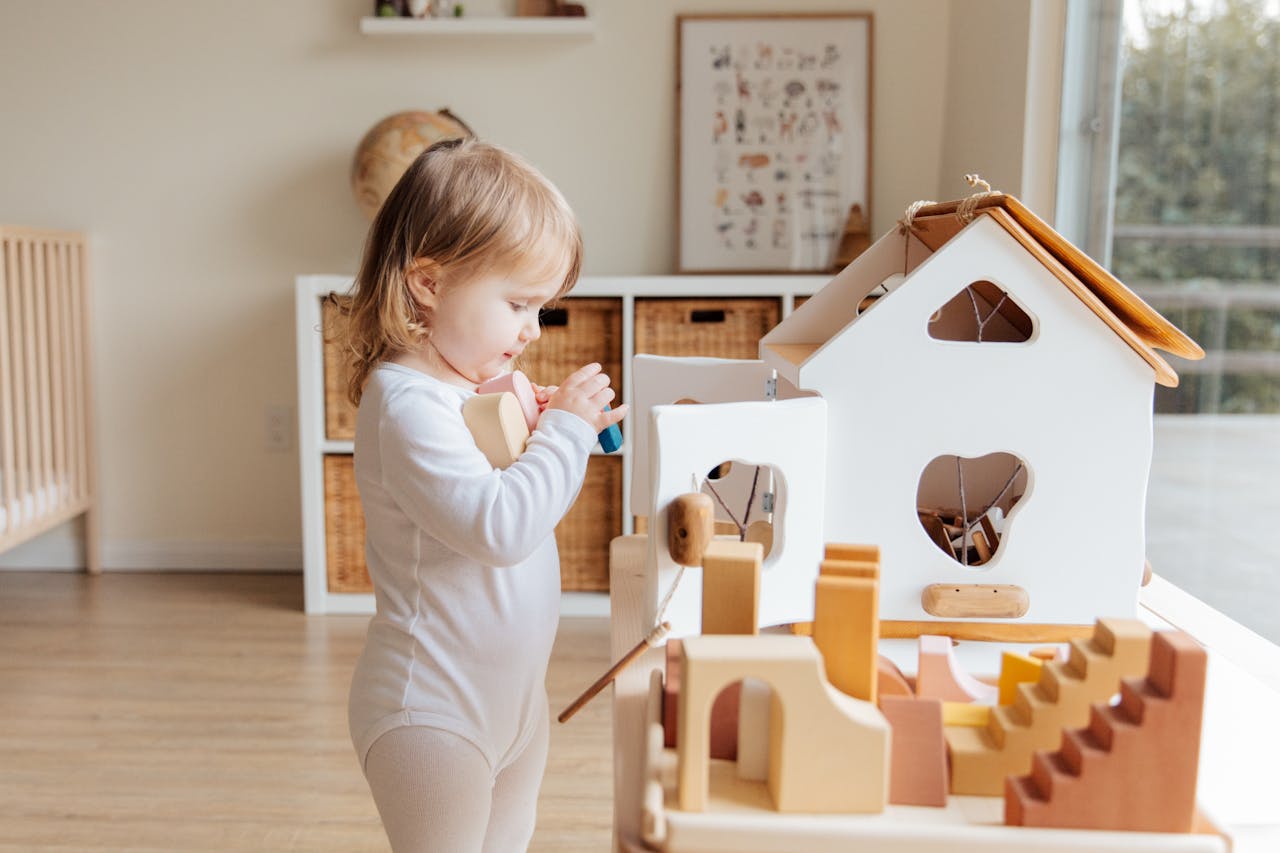 experience-01 Cute toddler engaging with wooden toys in a bright indoor setting.